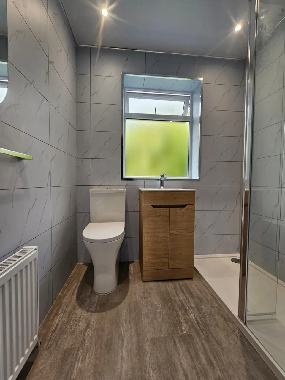 Compact shower room with oak vanity and marble-effect walls